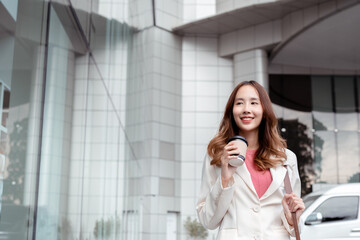 Fototapeta premium Beautiful asian female businesswoman use smartphone, Walk enjoy smiling while doing commuting in the modern city near office building outside..