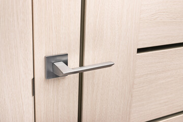 Close up of chrome gray metal door handle on light interior door.