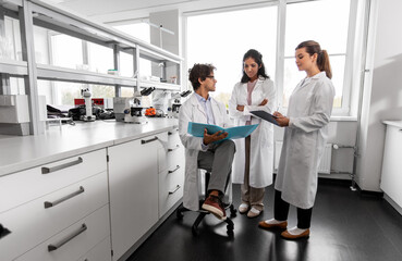 Obraz premium science research, work and people concept - international group of happy scientists with folder discussing report in laboratory