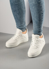 Casual comfortable white sneakers on female model in studio.