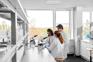 science research, work and people concept - international team of scientists with microscopes working in laboratory