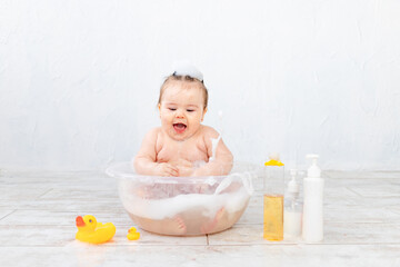 baby washes in a bowl with foam, space for text on bottles, baby hygiene