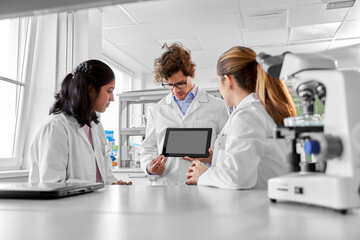 Fototapeta premium science research, work and people concept - international group of scientists with tablet pc computer working in laboratory