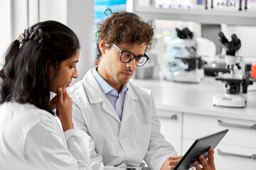 science research, work and people concept - international scientists with tablet pc computer...