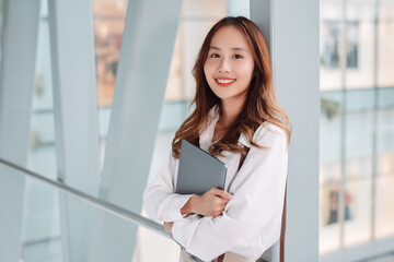 Beautiful asian female businesswoman hold laptop computer, Smart woman enjoy smiling while doing commuting in office workplace