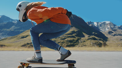 Cinematic downhill longboard session. Young woman skateboarding and making tricks between the curves on a mountain pass. Concept about extreme sports and people © oneinchpunch