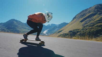 Cinematic downhill longboard session. Young woman skateboarding and making tricks between the curves on a mountain pass. Concept about extreme sports and people © oneinchpunch
