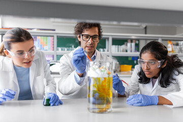 science research, work and people concept - international team of scientists with chemicals working in laboratory