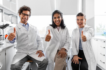 science, work and people concept - international group of happy scientists showing thumbs up in...