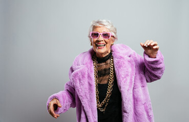 image of a beautiful and elegant old influencer woman. Cool grandmother posing in studio wearing fashionable clothes - obrazy, fototapety, plakaty