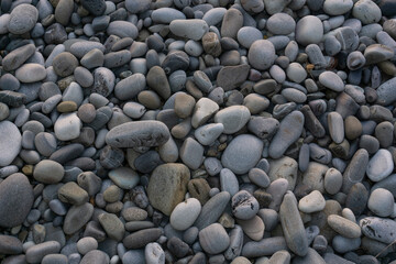 Sea stones background with small pebbles or stone in garden or in the seaside or on a beach. A close up view of rounded smooth polished pebble stones