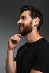 portrait of happy man with beard in black t-shirt smiling isolated on grey.