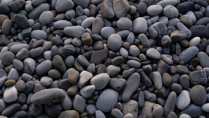 Fototapeta na wymiar Sea stones background with small pebbles or stone in garden or in the seaside or on a beach. A close up view of rounded smooth polished pebble stones