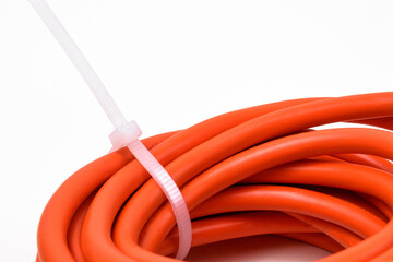 White cable ties on orange cable close up.