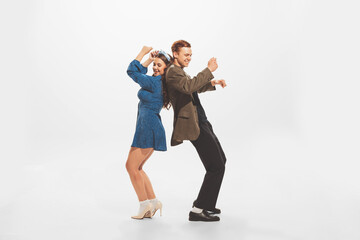 Portrait of young beautiful couple, stylish man and woman dancing at the retro party isolated over white studio background