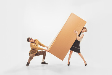 Portrait of young man and woman carrying giant cardboard boxes. New apartment furniture shopping....