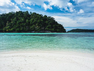Scenic view of Koh Rokroy Island white sand beach with crystal clear turquoise sea water and coral reef against summer blue sky. Near Koh Lipe Island, Tarutao National Marine Park, Satun, Thailand.