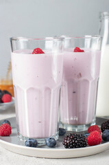 Smoothie from fresh berries, natural yogurt and honey in two tall glasses on gray background