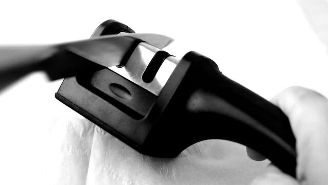 sharpening a kitchen knife in a manual knife sharpener