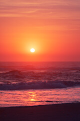Red sky at sunrise with the sun appearing over the ocean	