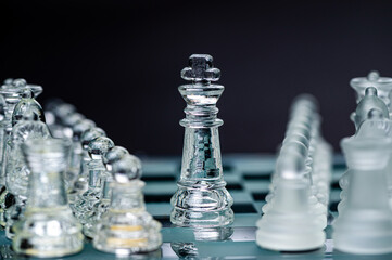 Transparent glass chess pieces on dark background. Leadership and  strategy concept, selective focus