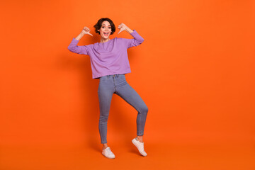 Full length photo of shiny sweet lady wear violet sweatshirt pointing thumbs herself empty space isolated orange color background