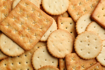 Many delicious crackers as background, top view