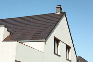 Fototapeta na wymiar Modern house with grey roof against blue sky, low angle view