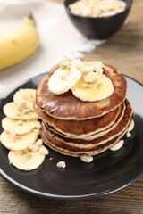 Obraz na płótnie Canvas Plate of banana pancakes on wooden table, closeup