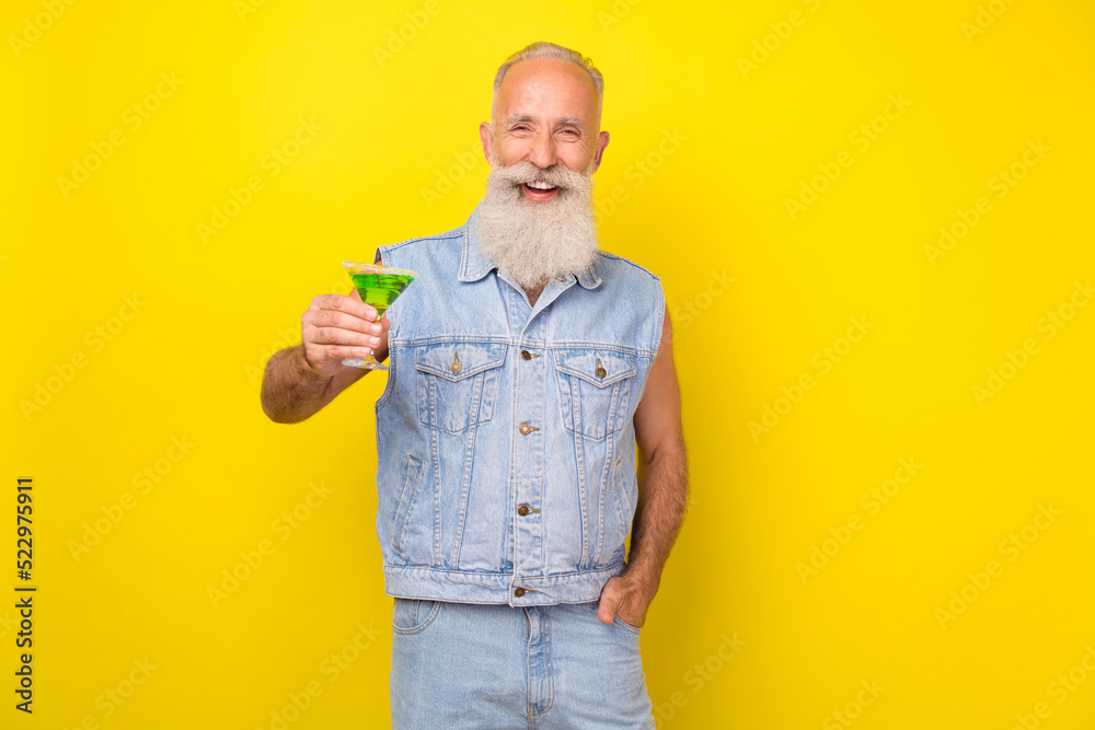 Sticker Photo of sweet pretty retired guy wear jeans waistcoat smiling rising cocktail glass isolated yellow color background