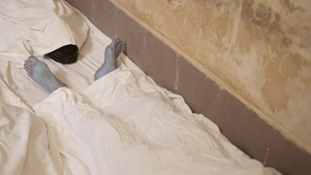 Corpse after disease, human life. Epidemic alert and infection. Scene in floor mortuary where corpses are taken away after death. Close-up of the feet of corpse covered in a sheet.