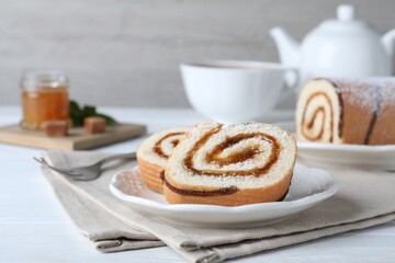 Tasty cake roll with jam on white wooden table