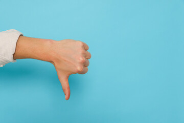 Man showing thumb down on light blue background, closeup. Space for text