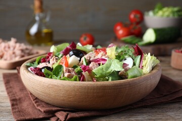 Bowl of delicious salad with canned tuna and vegetables on wooden table