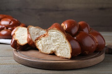 Cut homemade braided bread on wooden table, closeup. Traditional Shabbat challah