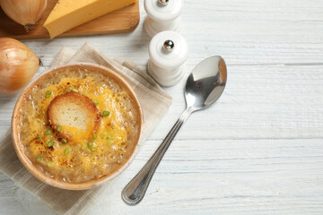 Tasty homemade french onion soup served on white wooden table, flat lay. Space for text