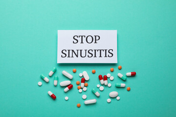 Card with phrase STOP SINUSITIS and different pills on turquoise background, flat lay
