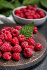 Fresh ripe raspberries with green leaf on table, closeup