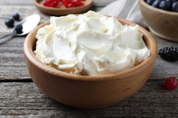 Tasty cream cheese and fresh berries on wooden table, closeup