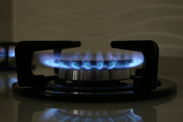 Gas burner of modern stove with burning blue flame, closeup