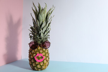Pineapple with sunglasses and paper lips on color background, space for text. Creative concept