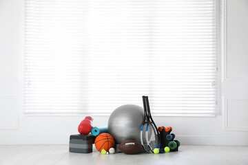Set of different sports equipment on white floor indoors, space for text