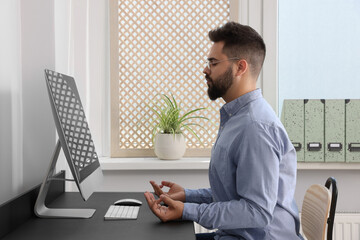 Young businessman meditating at workplace. Zen concept