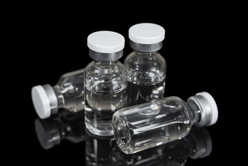 Glass capsules with liquid medicine on a black background