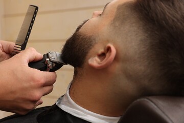 Professional hairdresser working with client in barbershop, closeup