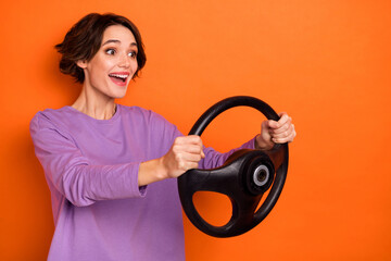 Profile photo of impressed positive girl hold wheel look excited empty space isolated on orange color background