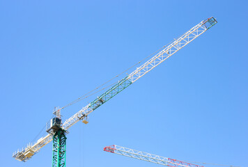 Construction crane tower on blue sky background. Crane and building working progress. Empty Space for text. Construction concept. Site. New buildings with a crane. Tower crane