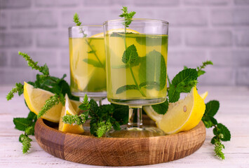 Lemon alcoholic drink with mint. Lemon liquor limoncello on a wooden tray.
