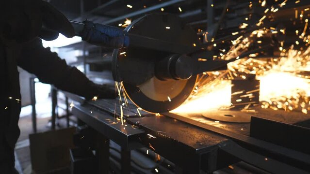 Close up of saw cutting machine cut metal. Many bright sparks fly from hot metal. Circular saw sawing steel in garage or workshop. Grinding metal at industrial professional manufacture. Slow motion