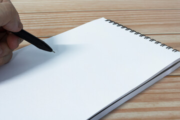 Hand with pen writing notebook on office desk table with. Copy space.